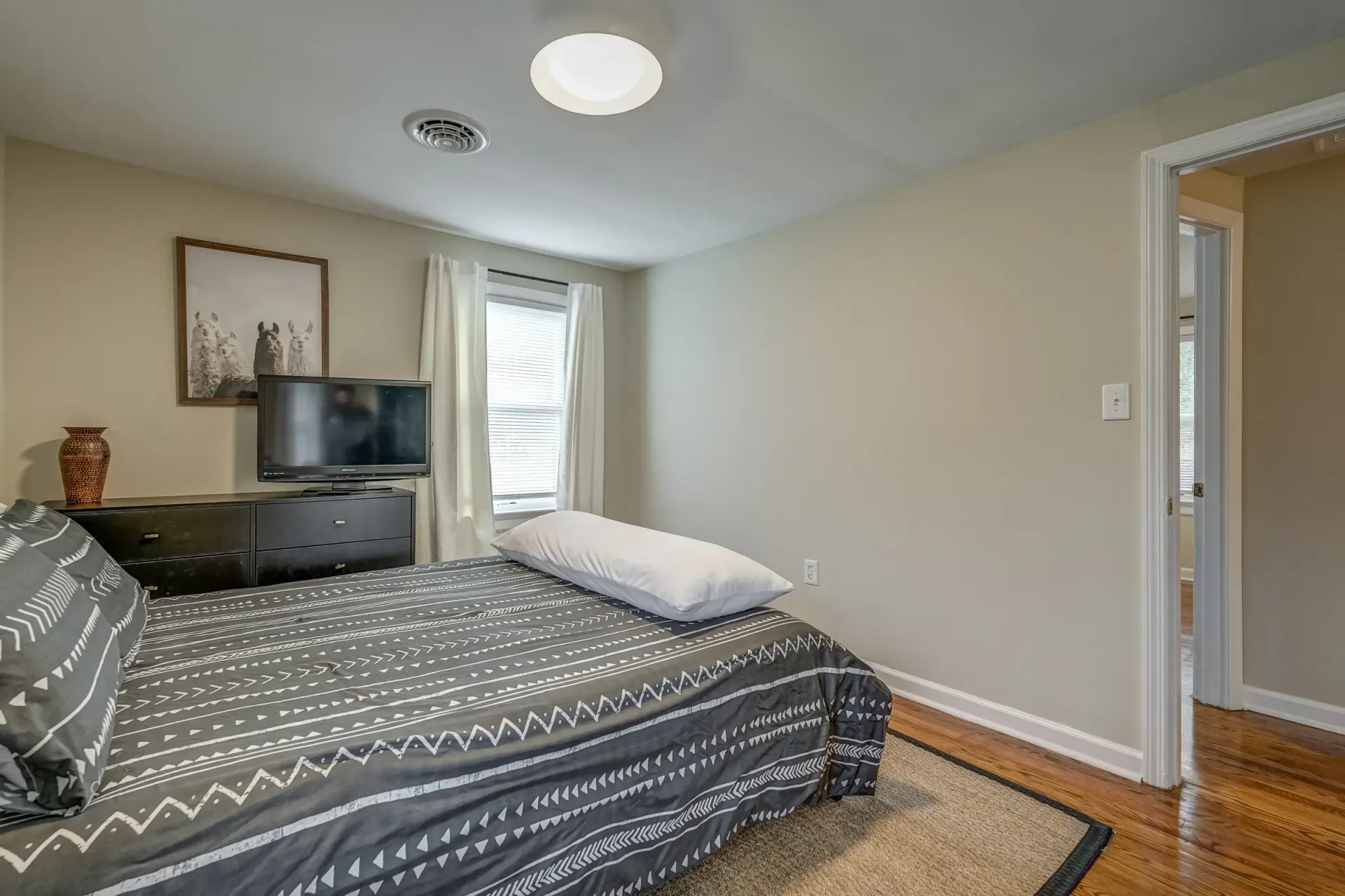 A bedroom with a bed , dresser , and television.