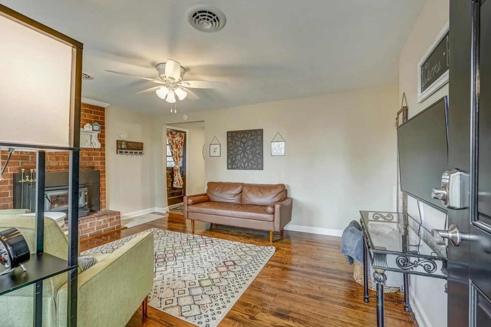 A living room with a couch , chair , rug and ceiling fan.
