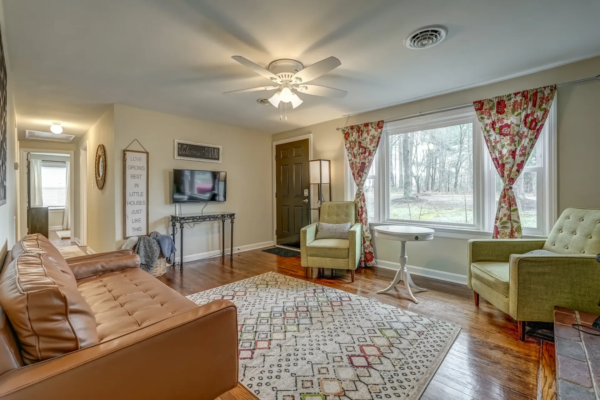 A living room with a couch , chairs , and a flat screen tv.
