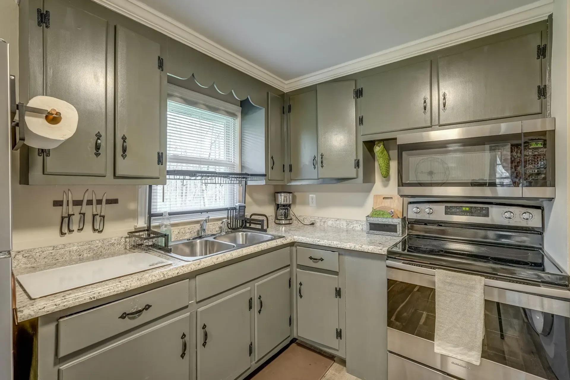 A kitchen with gray cabinets and stainless steel appliances