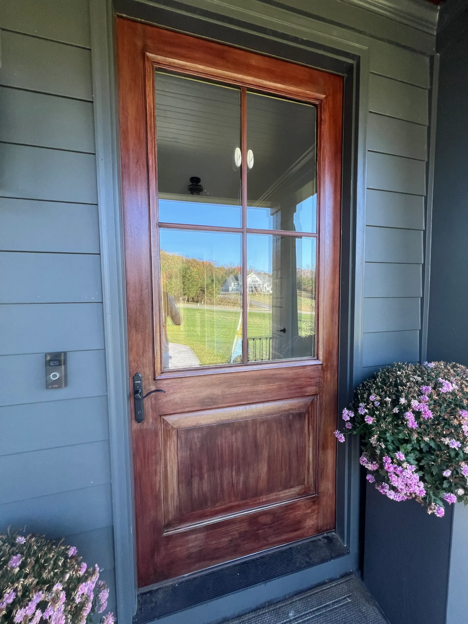 A wooden door with a glass window is on the side of a house.