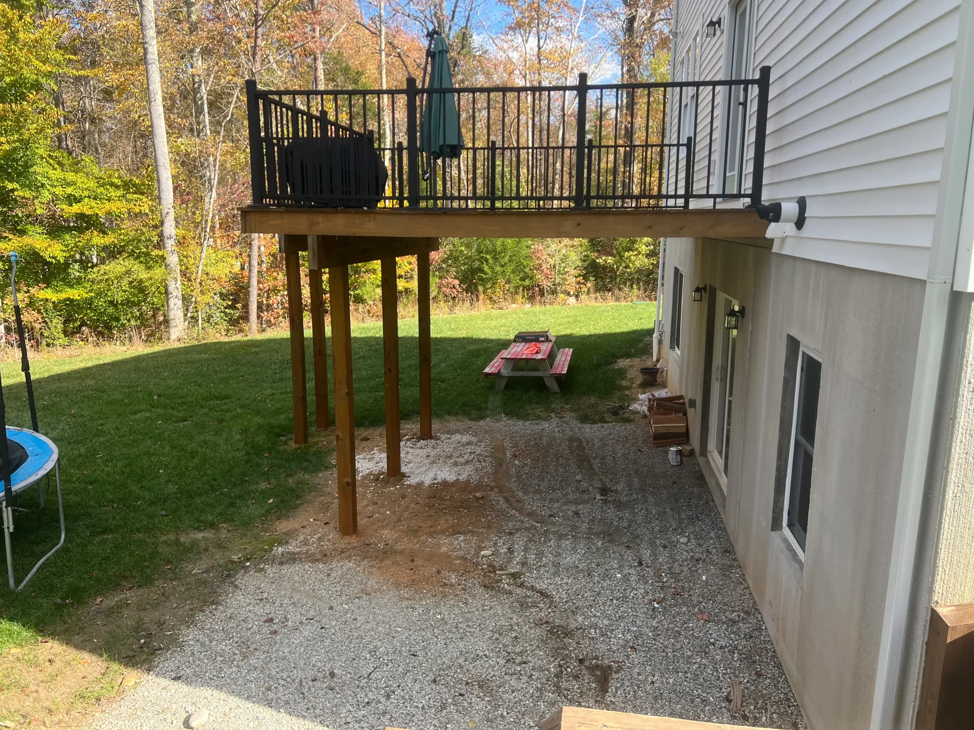 A house with a deck and a picnic table in the backyard.