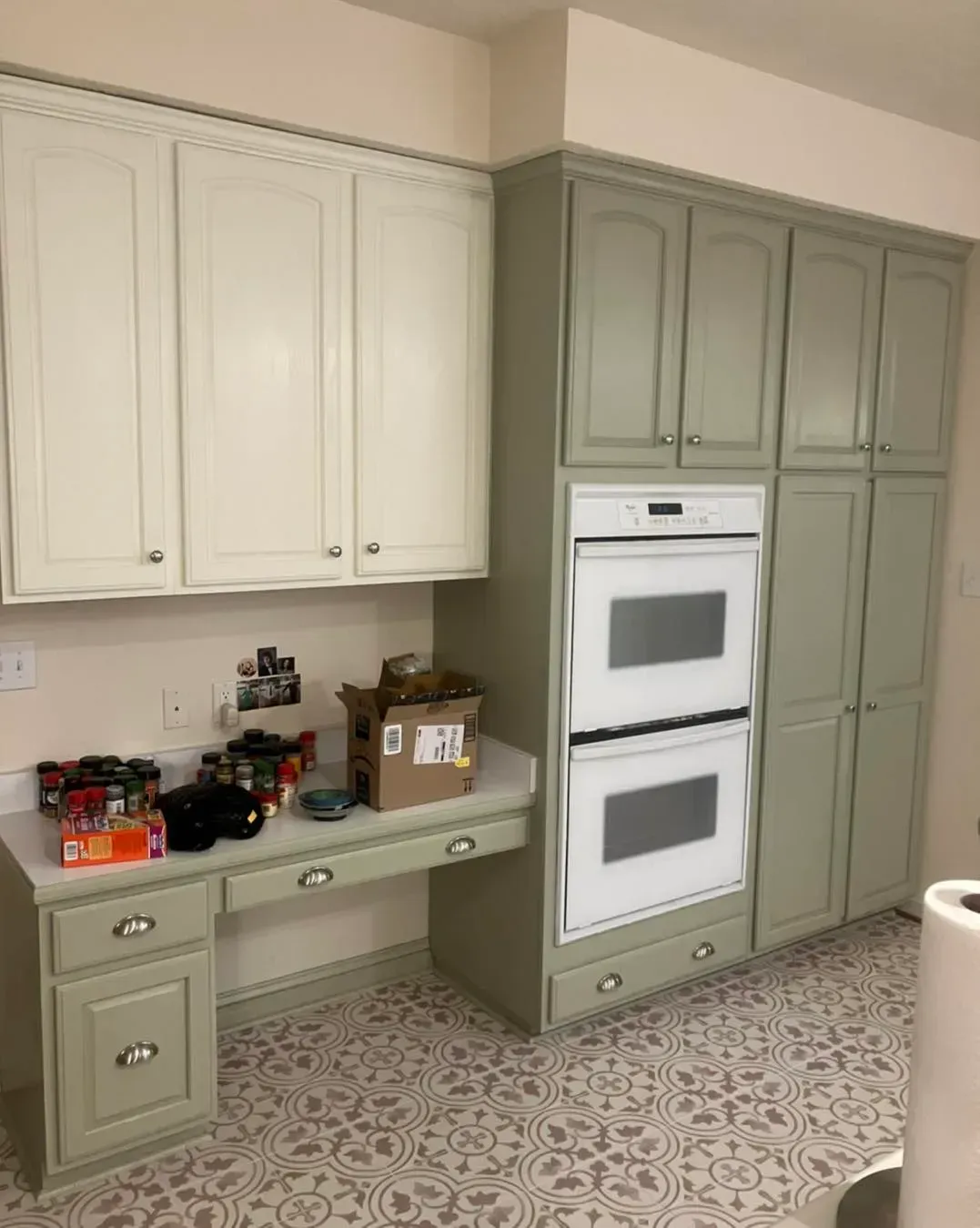 A kitchen with green cabinets and a double oven.
