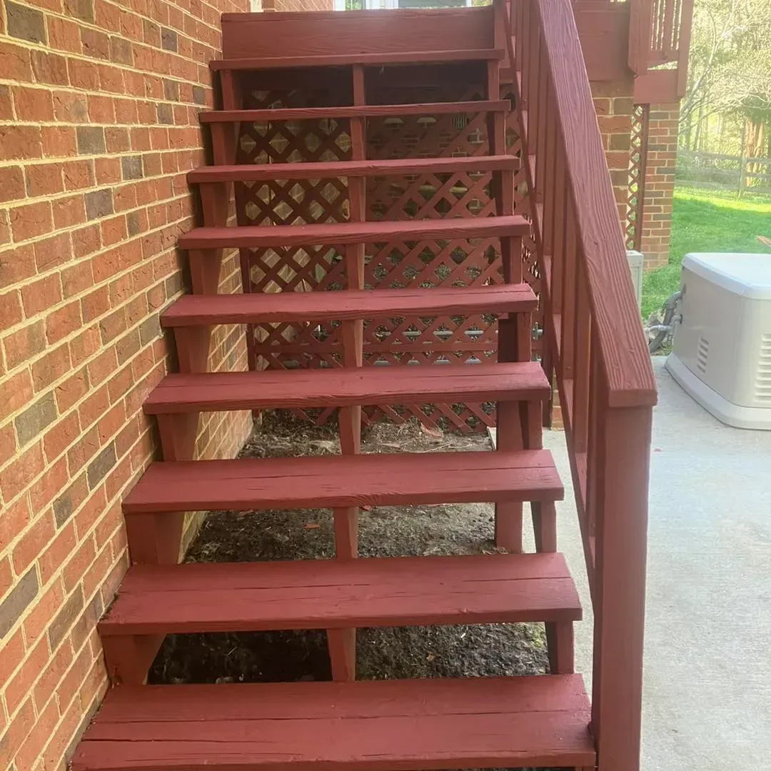 A set of red wooden stairs leading up to a brick building.