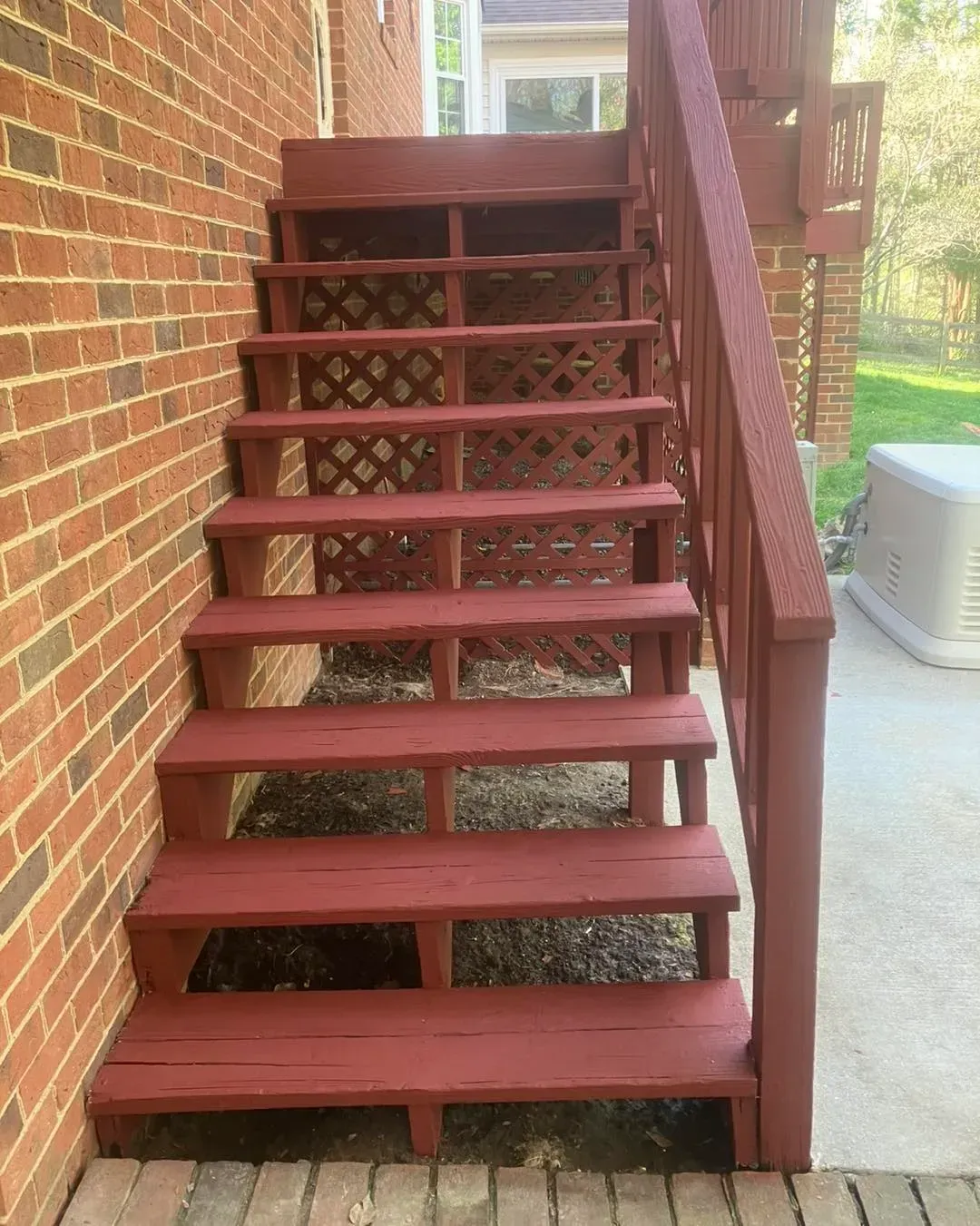 A set of red wooden stairs leading up to a brick building.