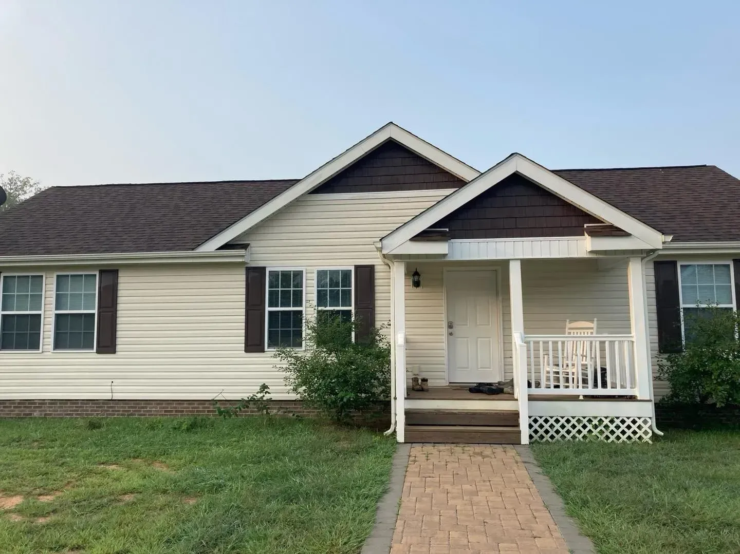 A white house with a brown roof and a porch