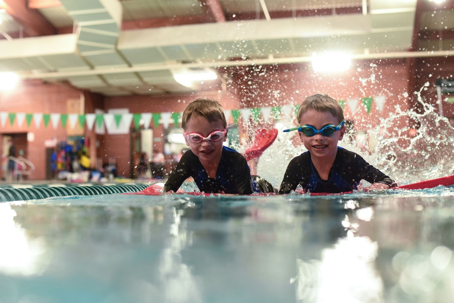 Two young boys are swimming in a swimming pool.