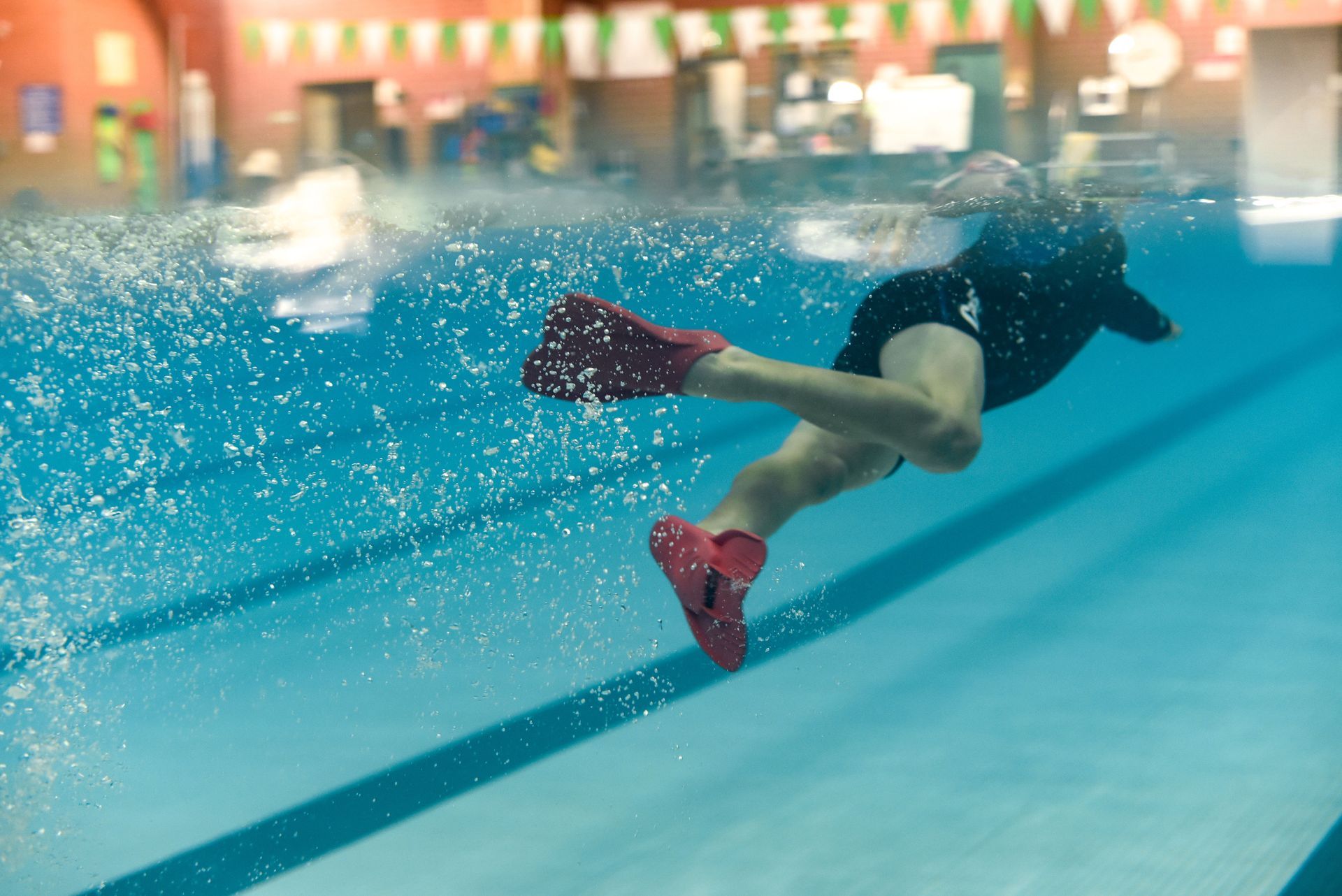 A person is swimming underwater in a swimming pool.