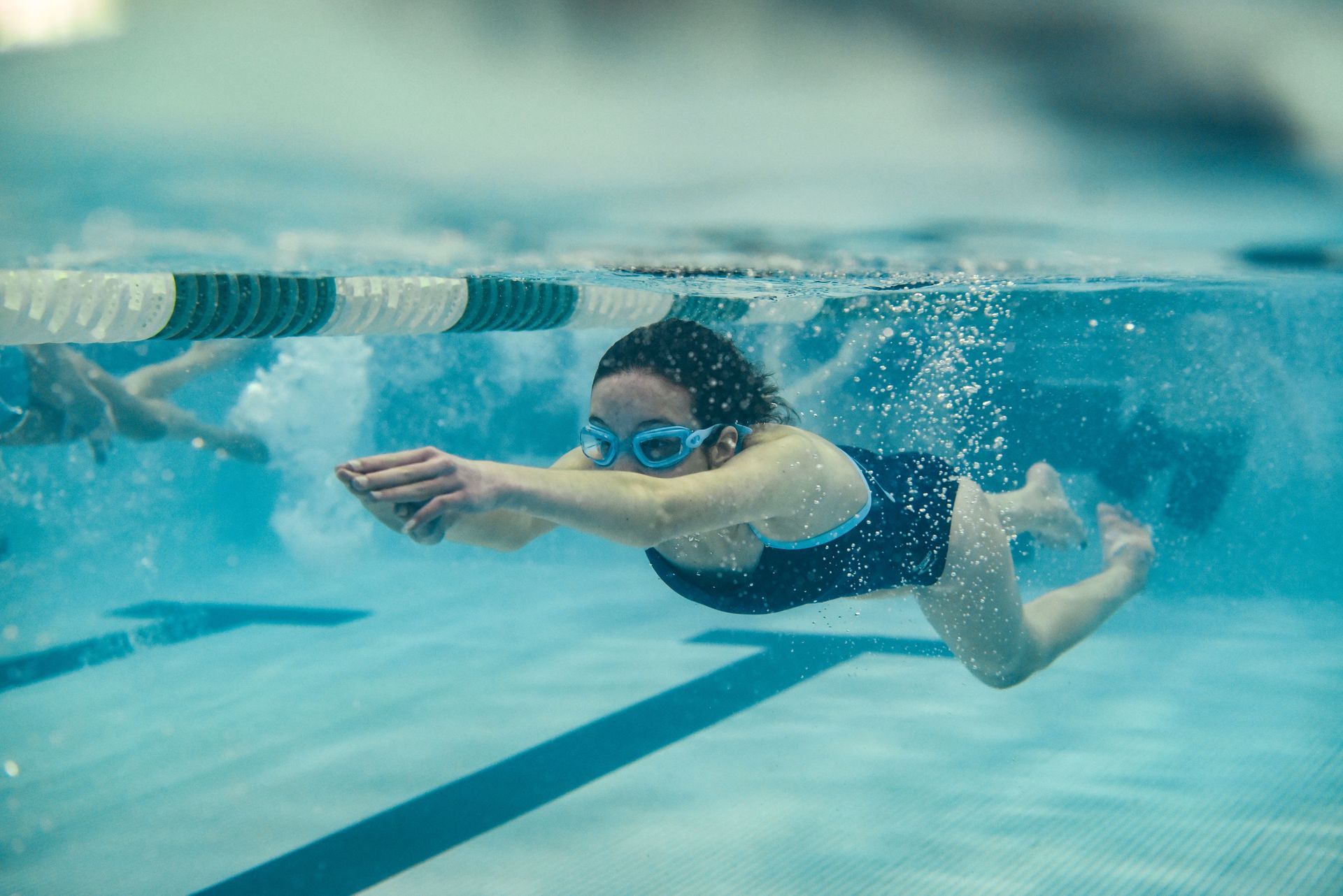 A woman is swimming underwater in a swimming pool.