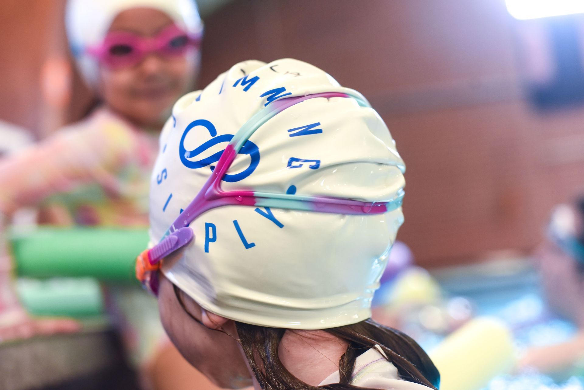 A young girl wearing a swim cap and goggles.