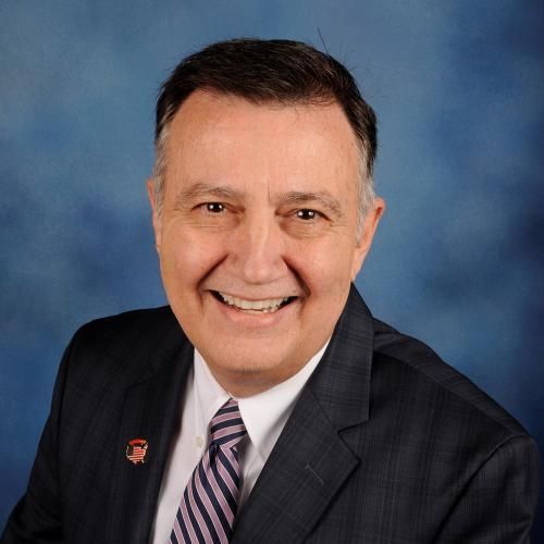 A man in a suit and tie is smiling for the camera