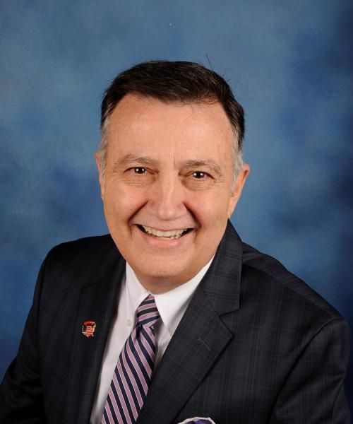 A man in a suit and tie is smiling for the camera