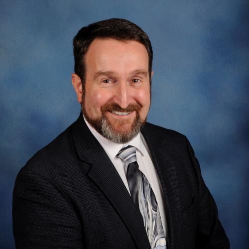 A man in a suit and tie is smiling for the camera