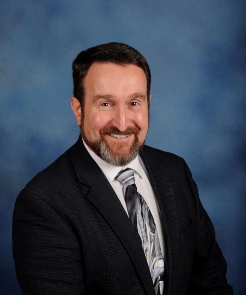 A man with a beard is wearing a suit and tie