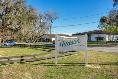 A sign that says hudson is in the middle of a grassy field.
