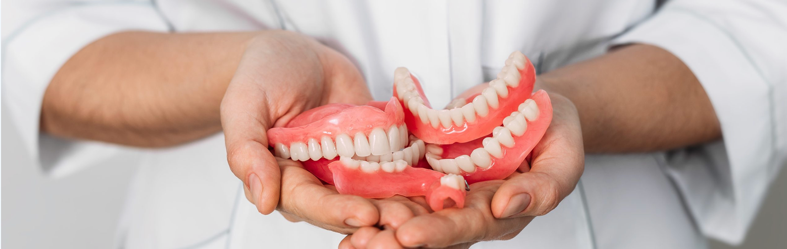 Hands holding multiple dentures.