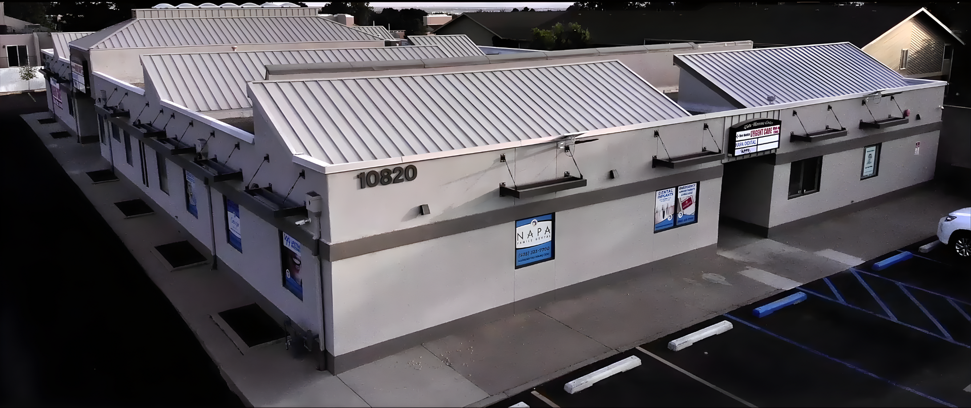 Exterior view of a commercial building with a metal roof and parking lot. Address number 10620 visible.