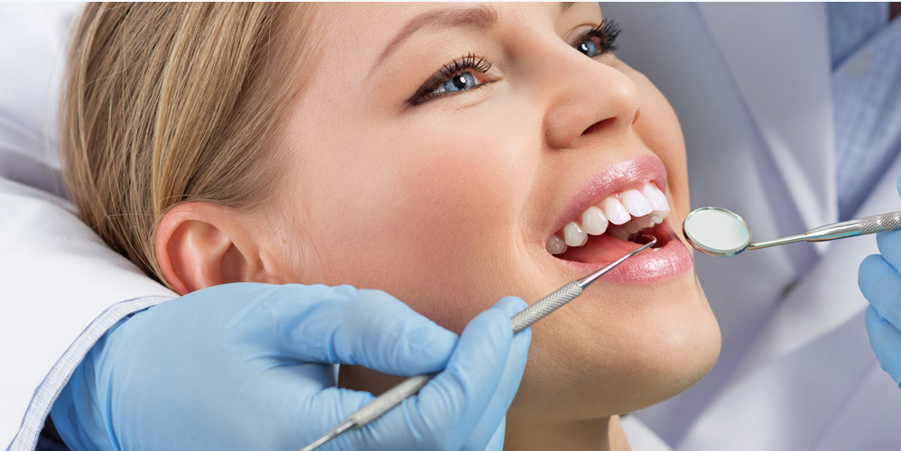 Woman at dentist, mouth open, smile. Dentist holding tools, checking teeth.