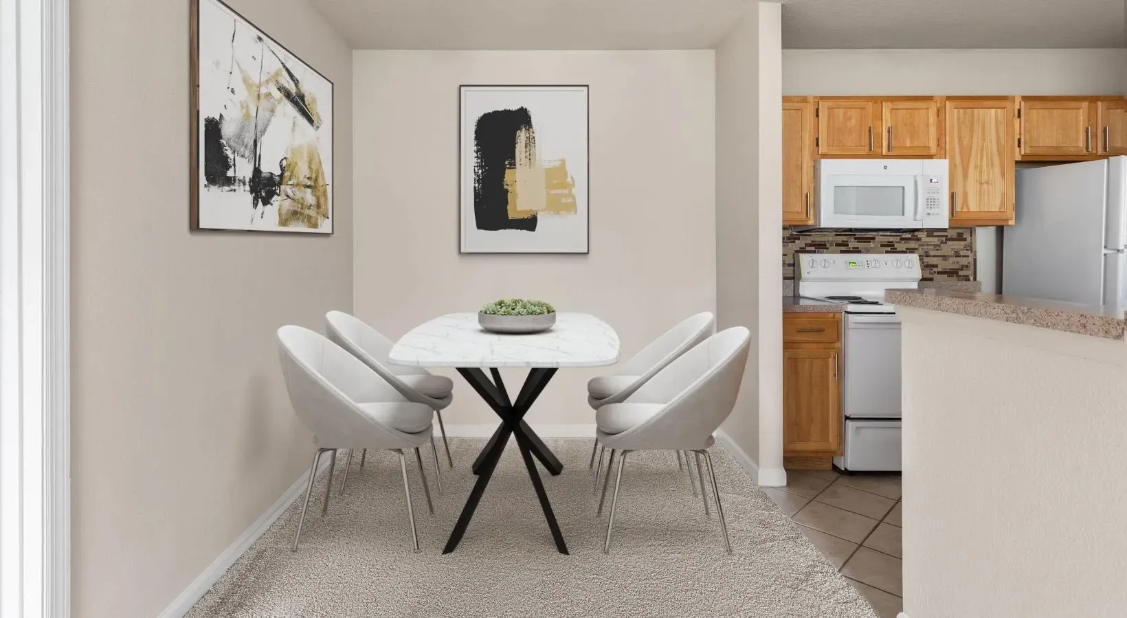 A dining area with a modern white table, four grey chairs, and two framed abstract artworks, next to a wood-cabinet kitchen.
