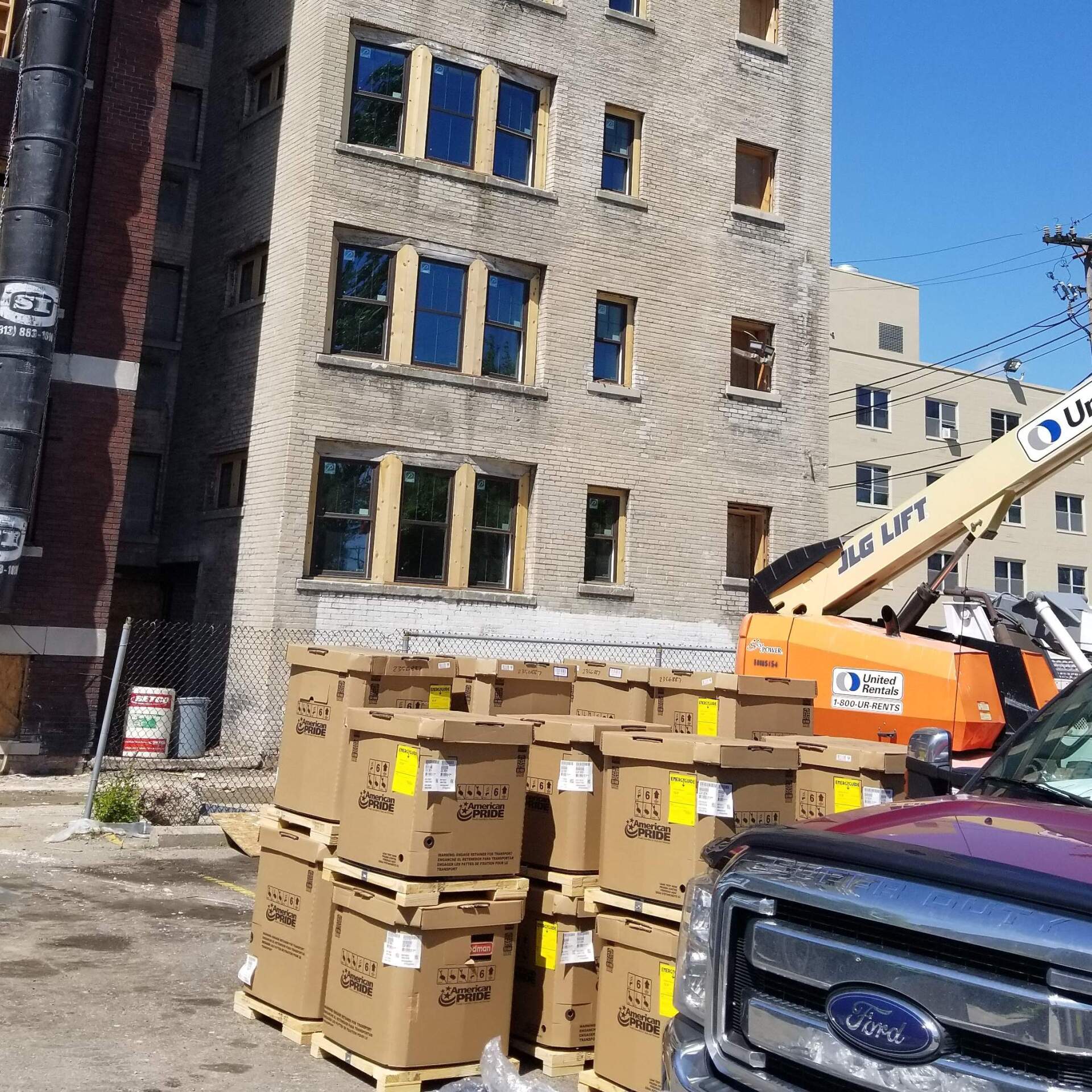 Building undergoing renovation, with stacked boxes in front and a cherry picker.
