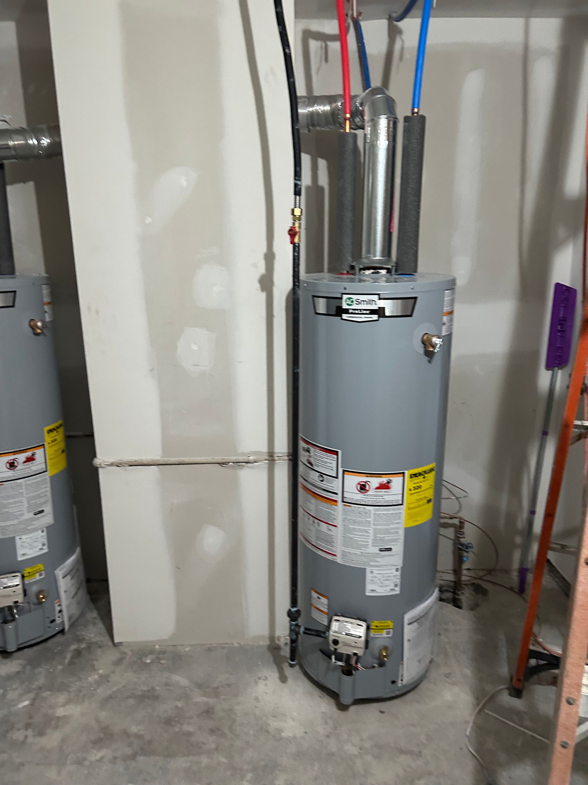 A gray water heater in a utility room with water pipes and a ladder.