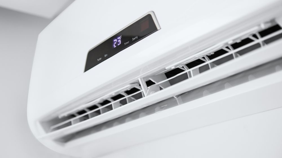 White wall-mounted air conditioner unit with digital display showing 23 degrees.