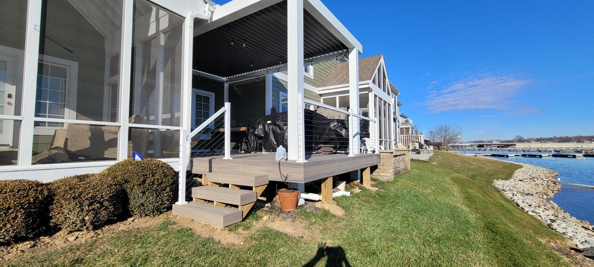 A house with a screened in porch next to a body of water .