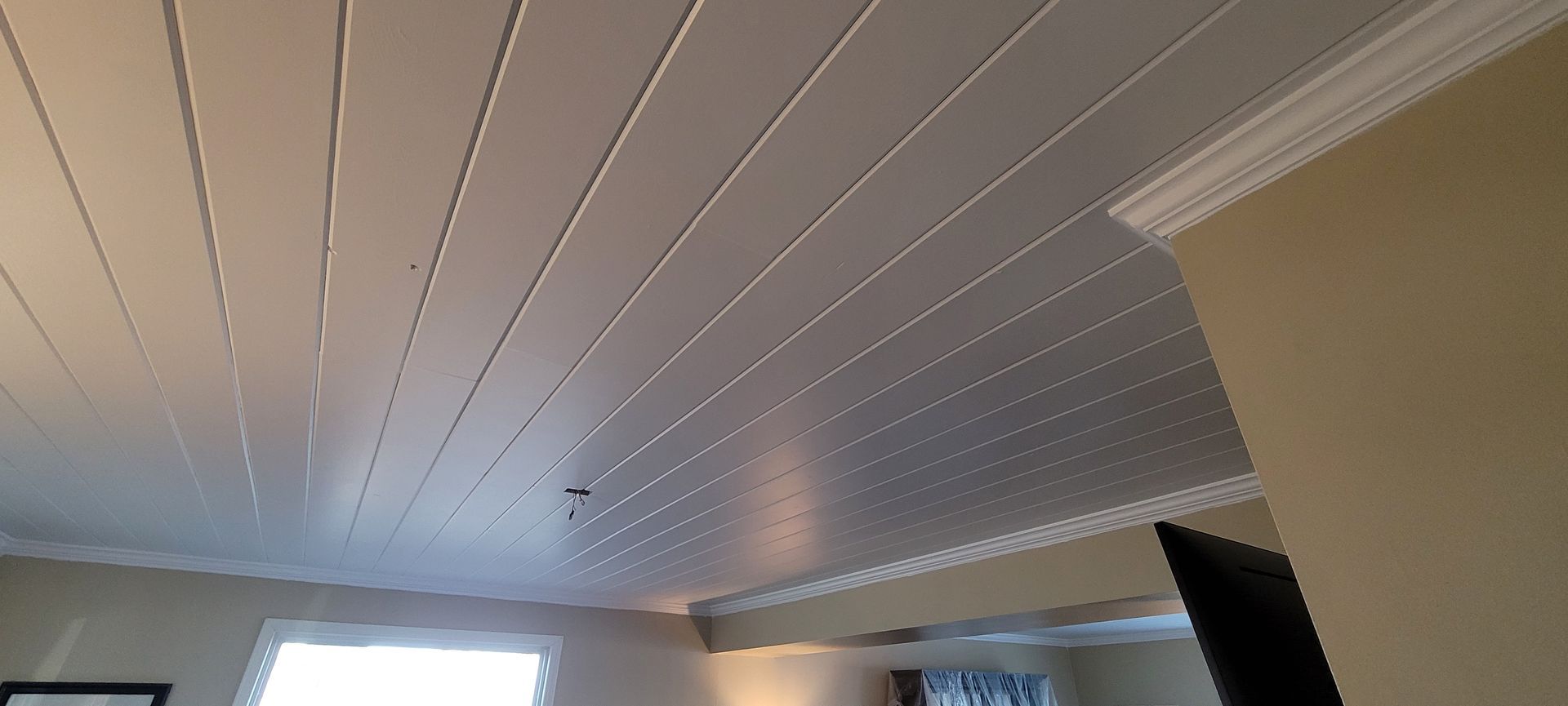 A living room with a white ceiling and a window .