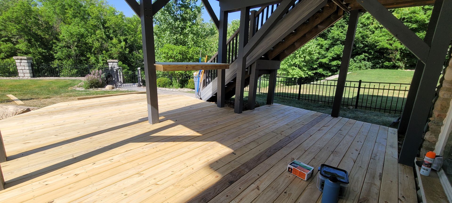 A wooden deck with a staircase and trees in the background .