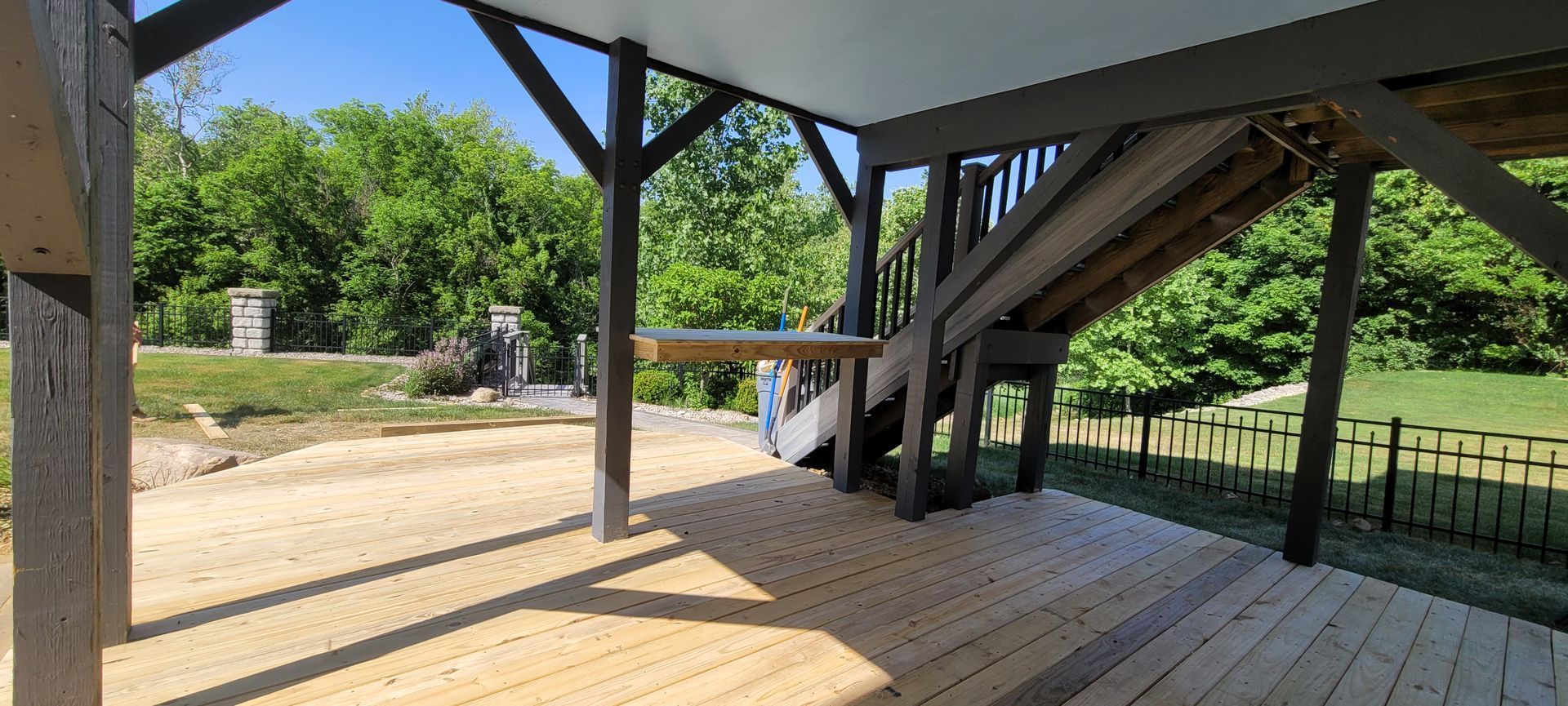 A wooden deck with a staircase leading up to it and trees in the background .