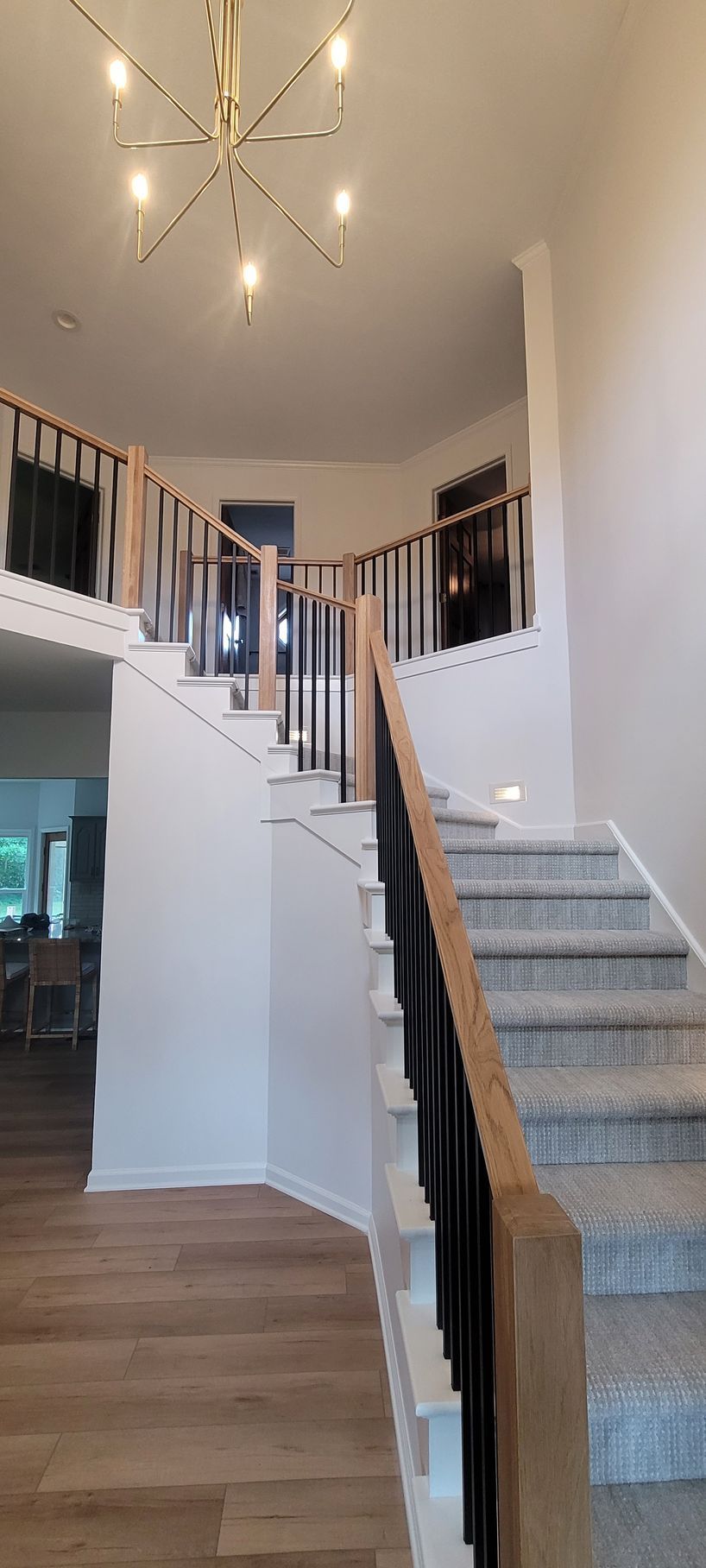 A staircase in a house with a chandelier hanging from the ceiling .