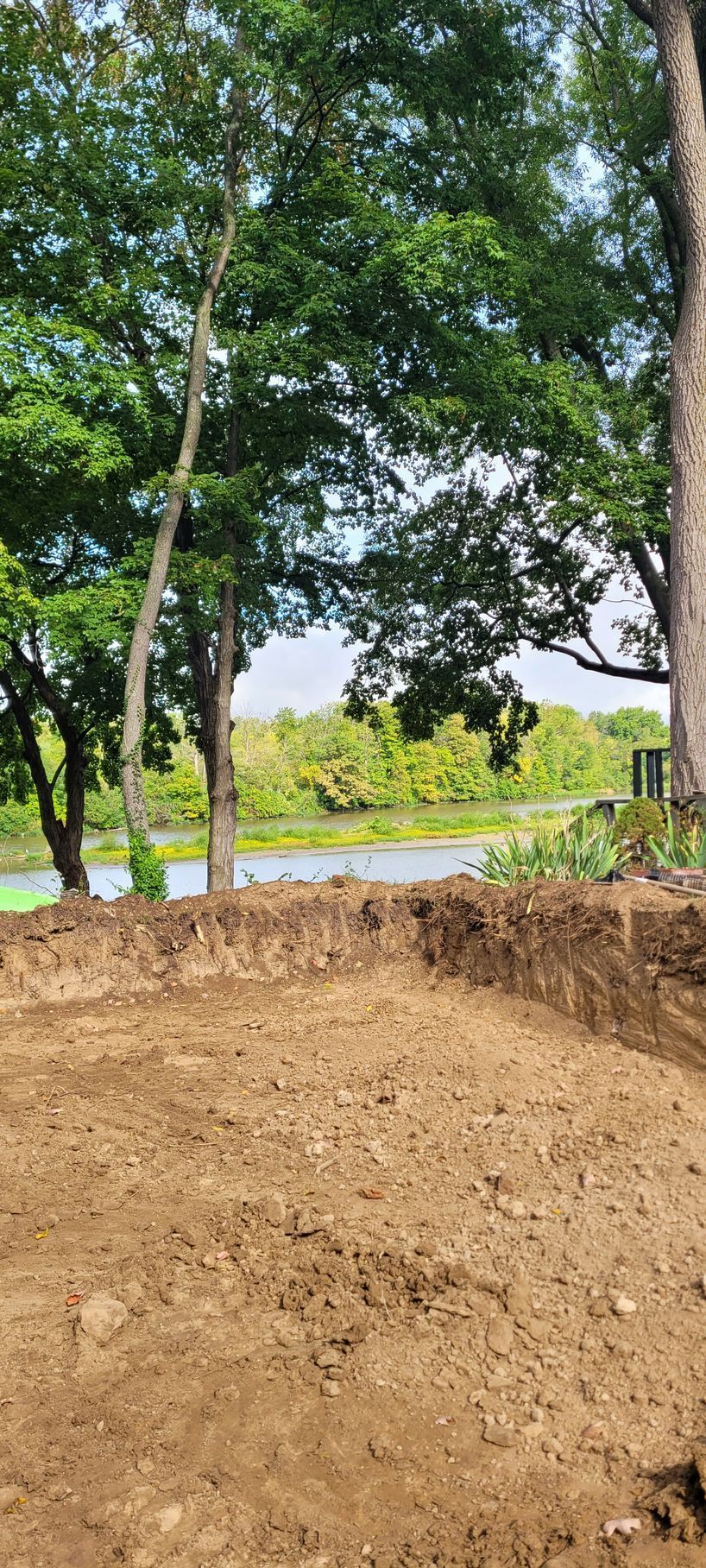 A dirt field with trees in the background and a body of water in the background .
