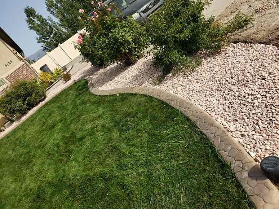 A lush green lawn with a concrete curb and gravel.