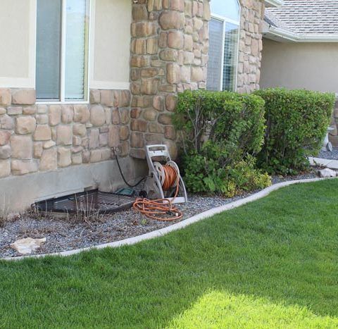 A hose reel sits in front of a stone house