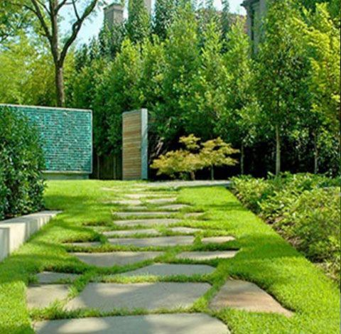 A stone walkway surrounded by lush green grass and trees