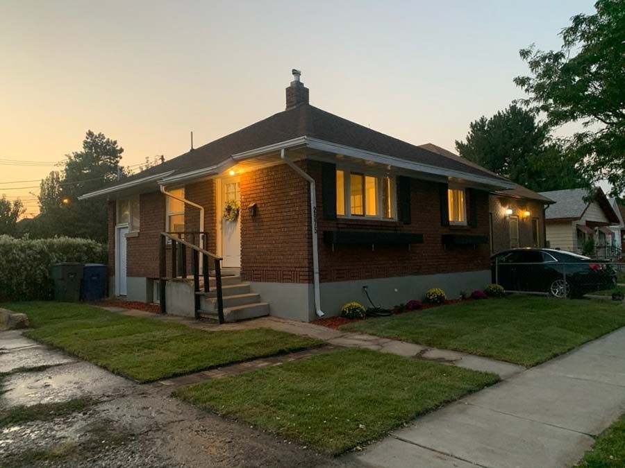 A small brick house with a car parked in front of it