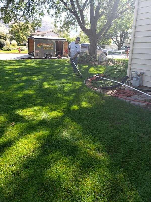 A man is standing in a yard next to a trailer.