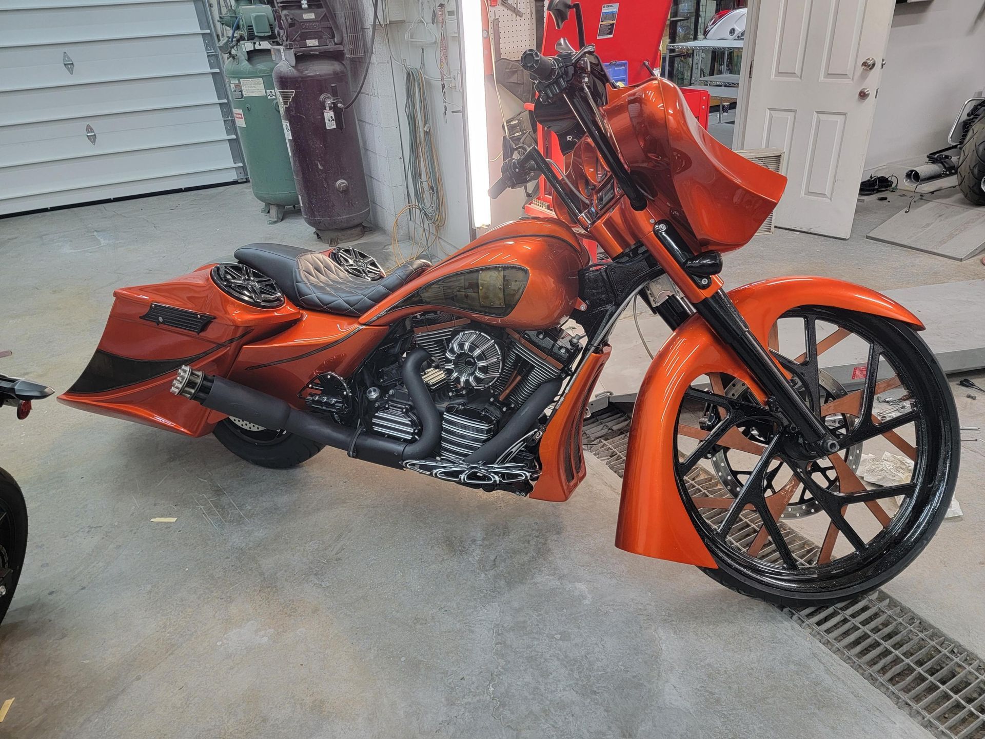 Orange custom motorcycle with black accents in a garage.