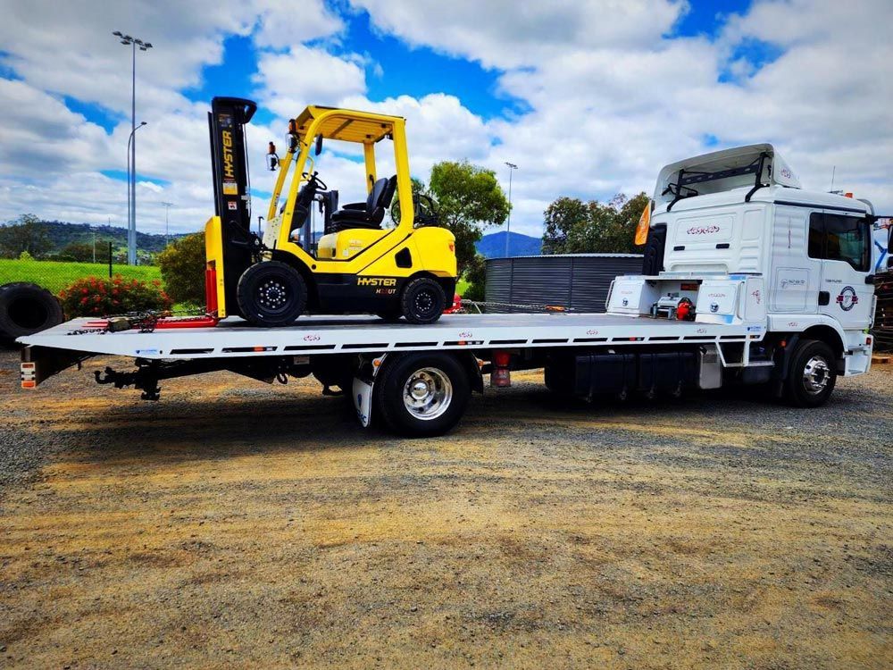 A Flatbed Truck Carrying A Forklift