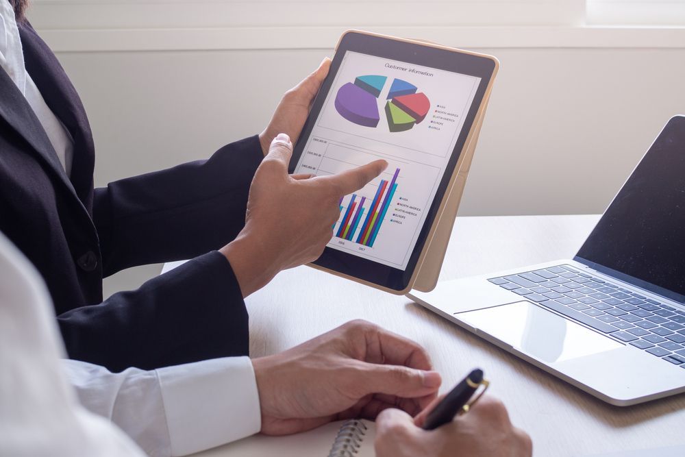Two People Reviewing Financial Data Displayed on a Tablet and Laptop — Blue Chip Bookkeeping in Newcastle, NSW
