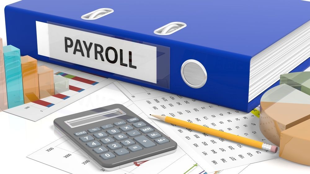 Payroll Word On Blue Binder And A Calculator Placed On Table — Blue Chip Bookkeeping In Cranbrook, QLD