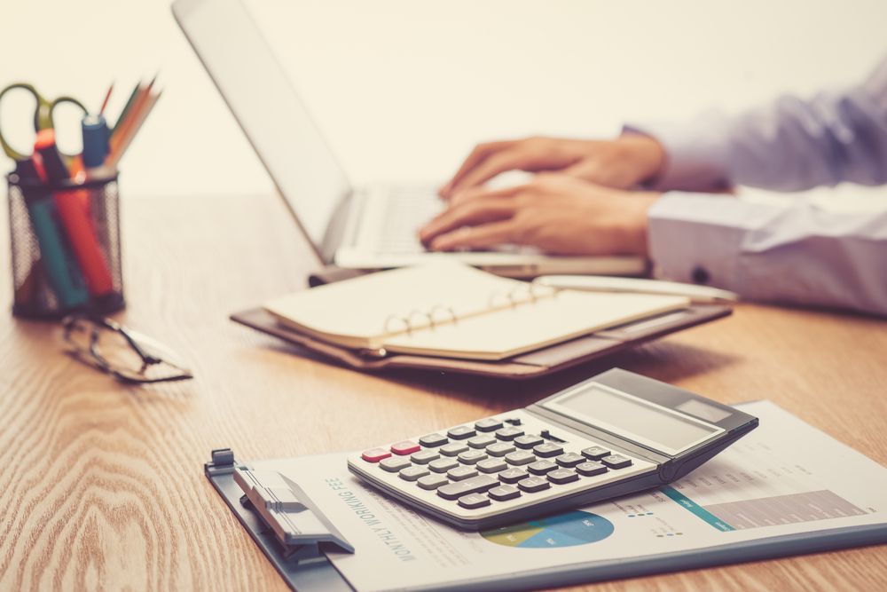 Hands Typing on a Laptop at a Desk With a Calculator, Notebook, and Pencils — Blue Chip Bookkeeping in Cairns, QLD