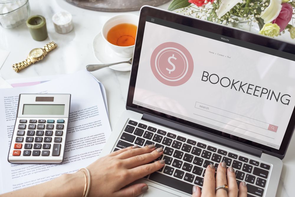 A Woman Is Typing On A Laptop Computer With The Word Bookkeeping On The Screen — Blue Chip Bookkeeping In Cranbrook, QLD