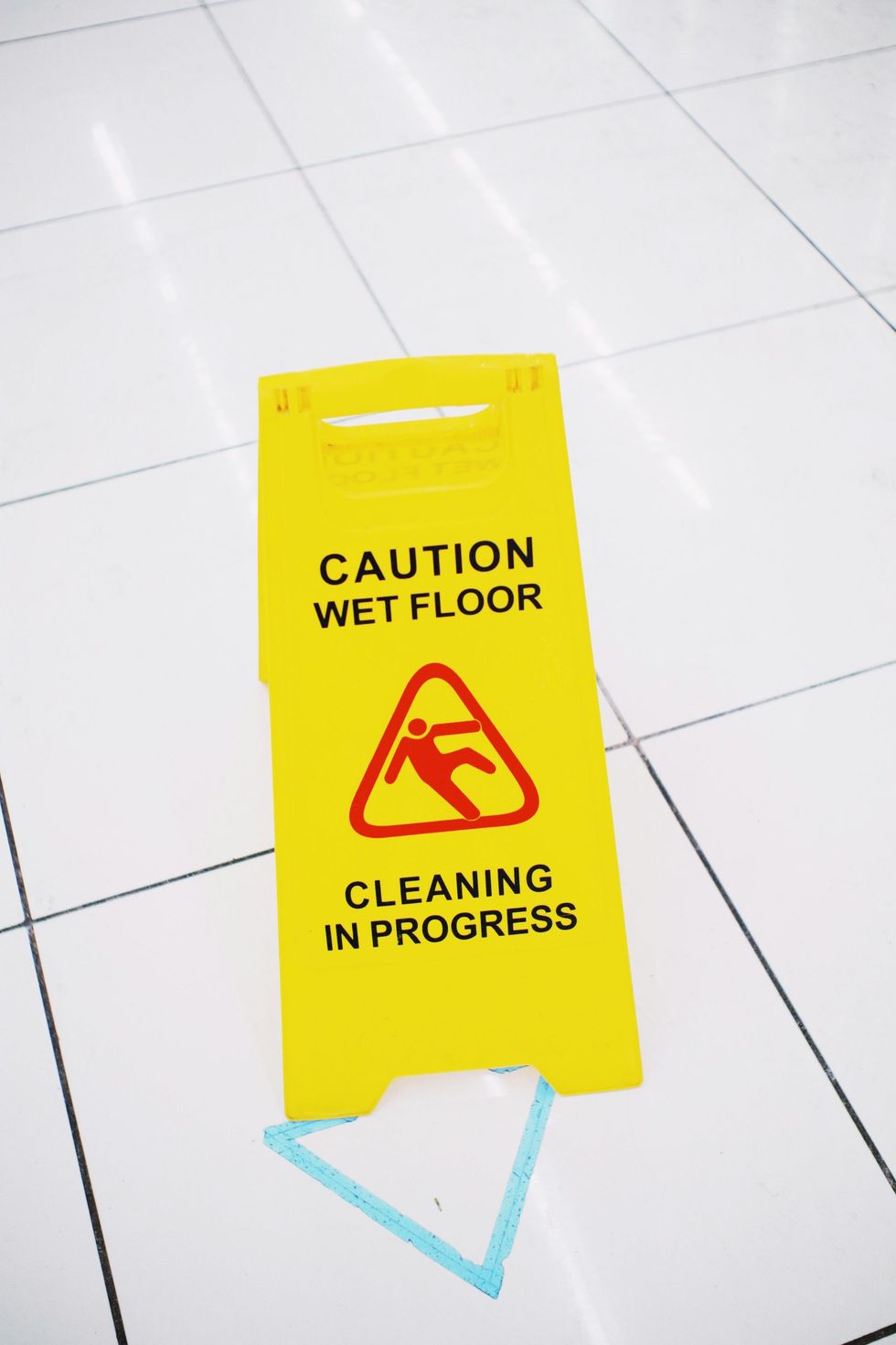 Yellow caution wet floor sign on a tiled floor reading “Cleaning in progress.”
