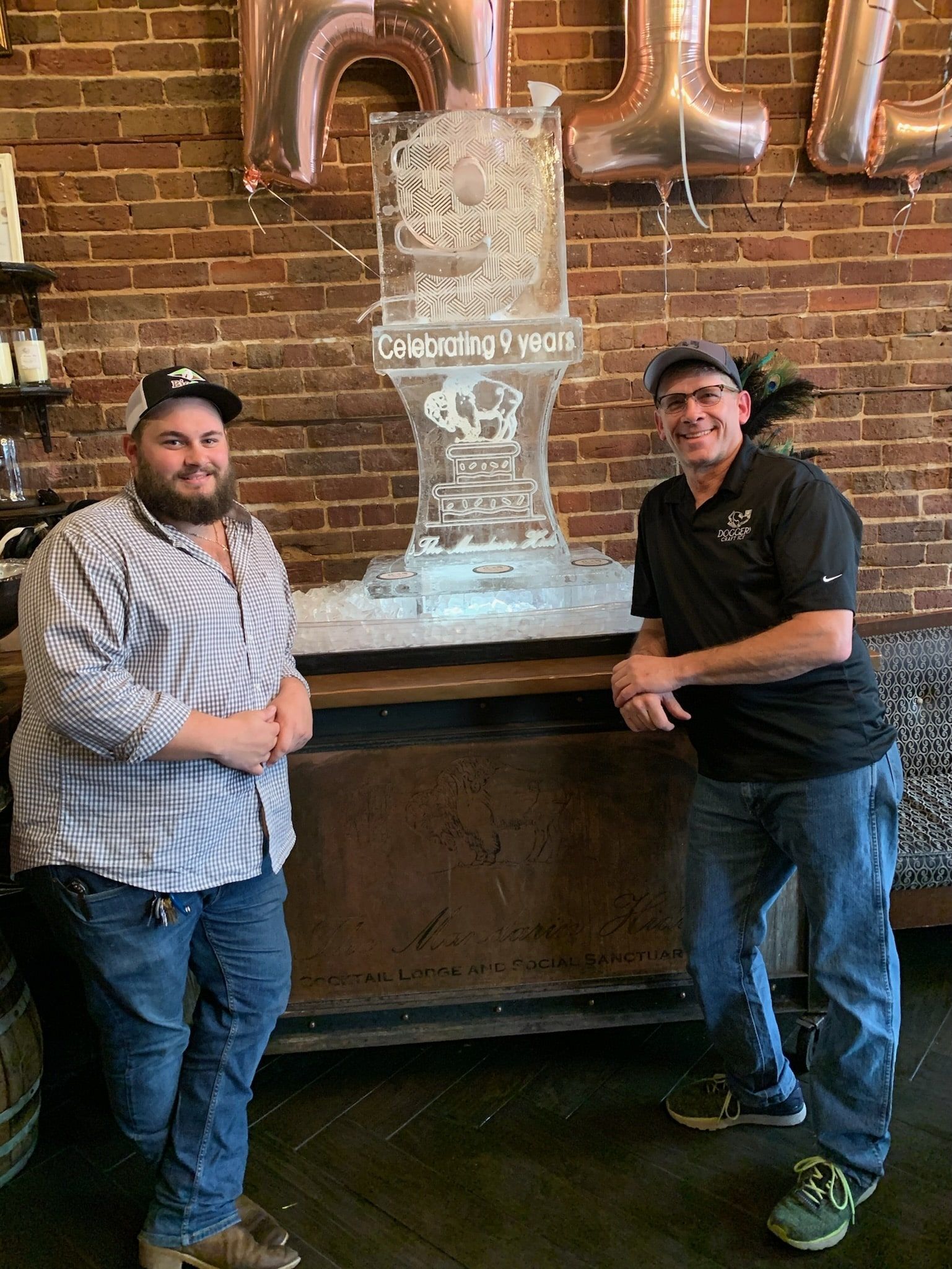 Two Men Standing in front of an Ice Sculpture