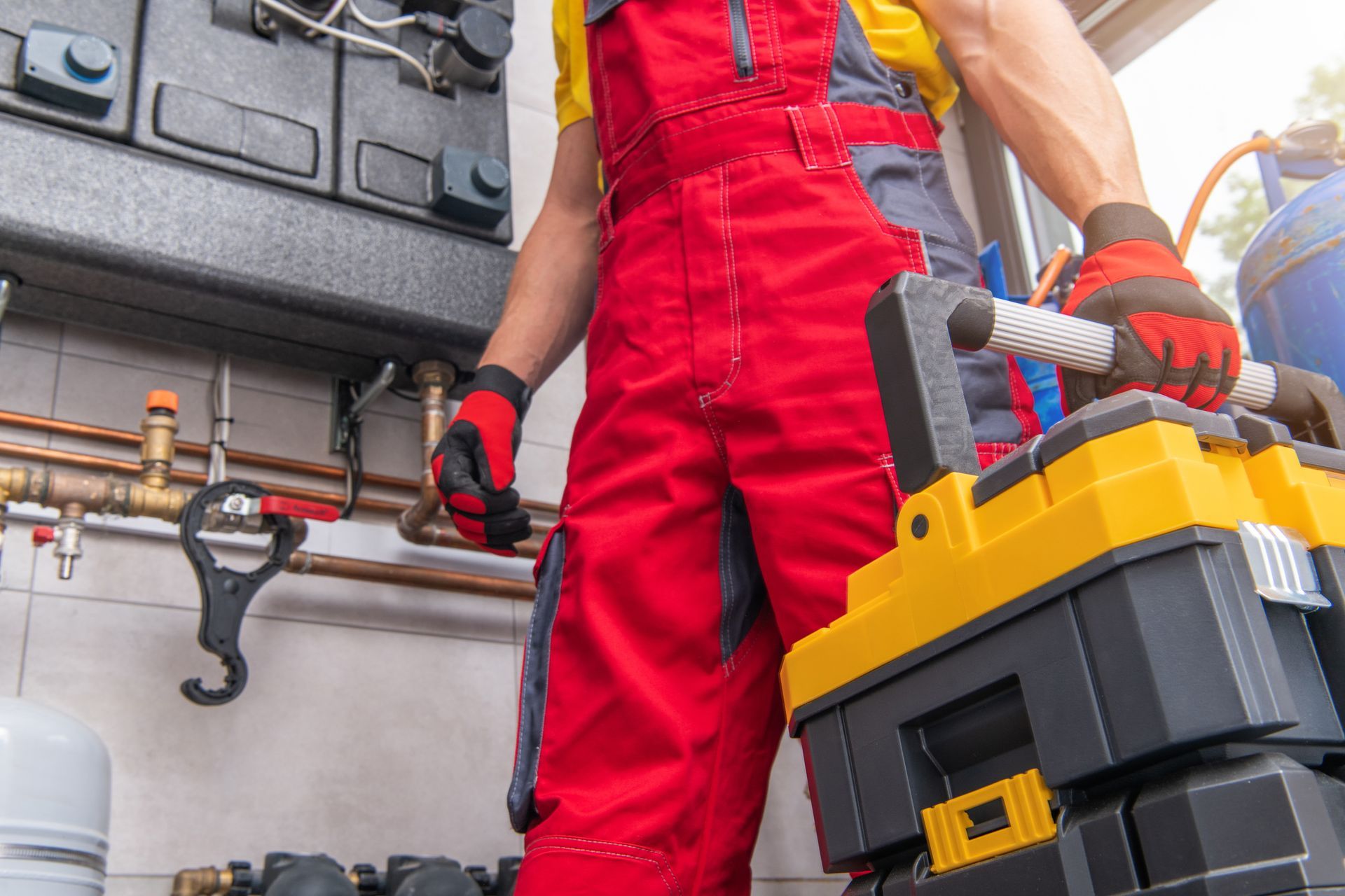 a man in red overalls is standing next to a toolbox .