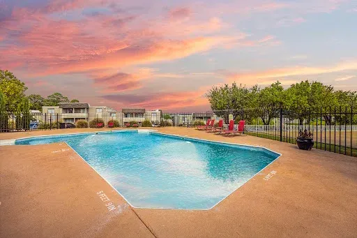 A large swimming pool with a fence around it at sunset.