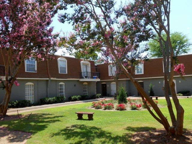 A brick apartment building with a bench in front of it
