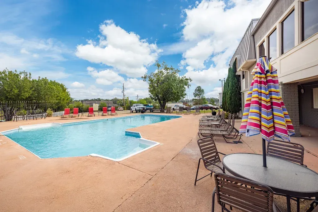 A large swimming pool with a table and chairs in front of it.