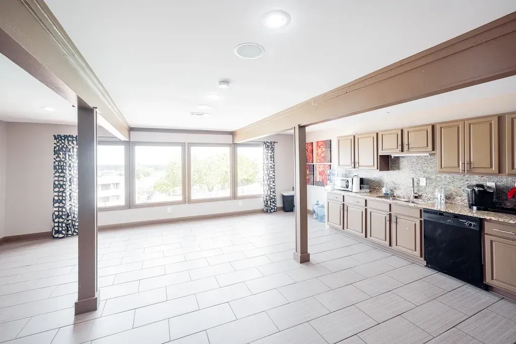 A large empty room with a kitchen and a lot of windows.